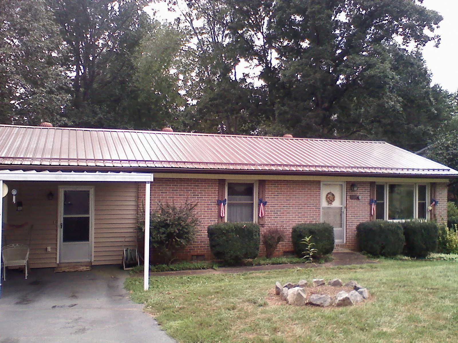 Bronze metal roof and carport on a brick ranch home — Roof Repair work by our crew in Bristow